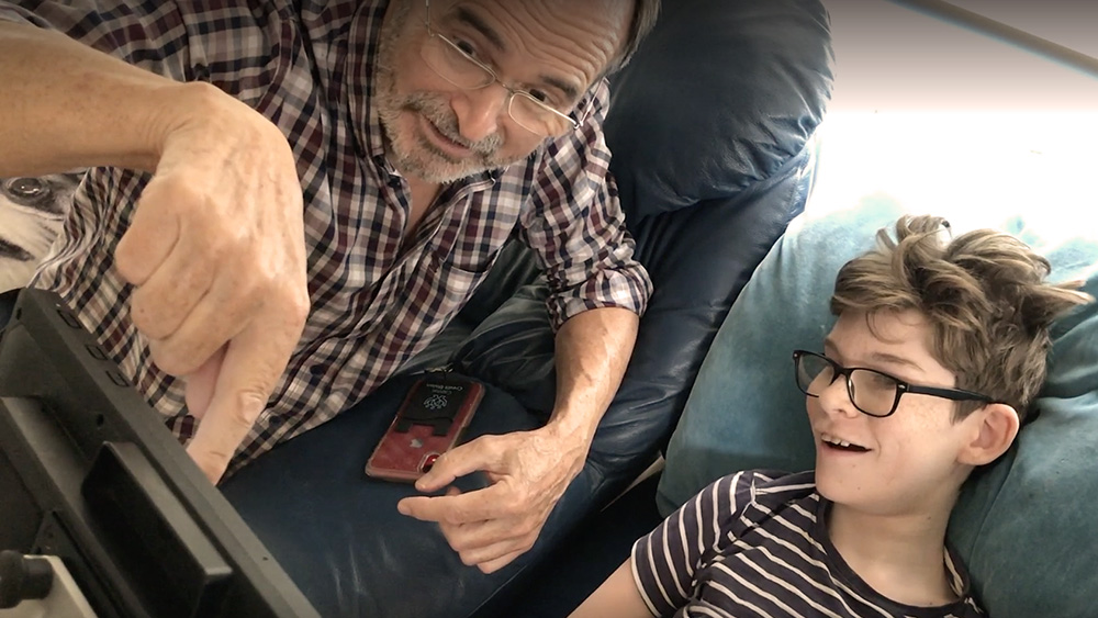 Man points at screen, smiling boy looks on