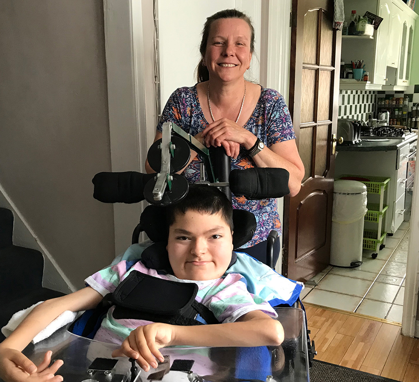 Smiling woman behind boy in wheelchair