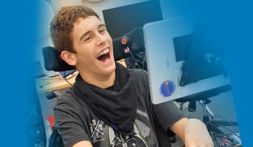 Seated young man smiling at a computer screen