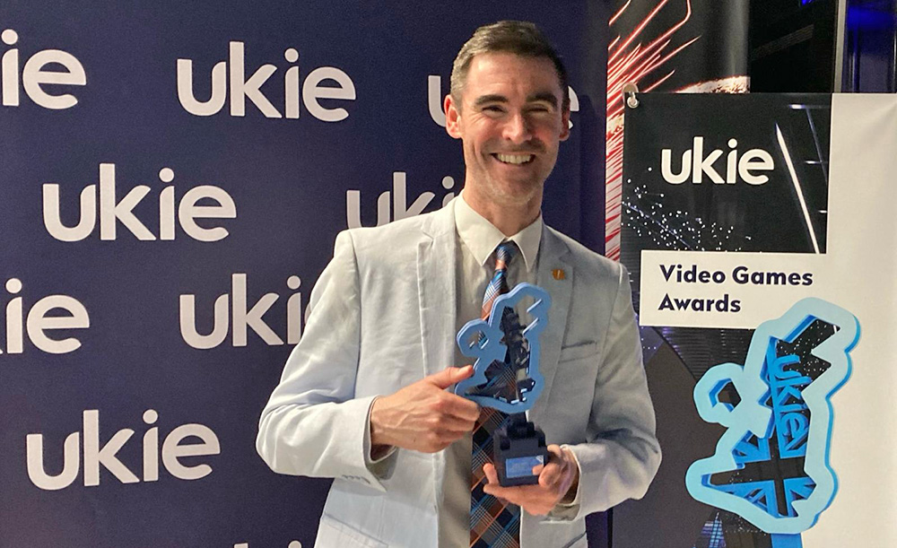 Smiling man in suit holding award trophy